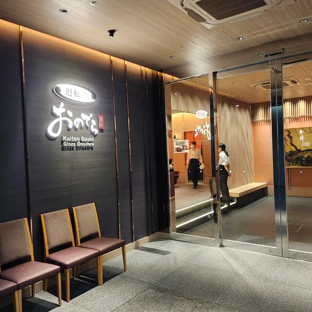 회전스시 긴자 오노데라 오사카점의 대기 의자와 밝은 간판이 있는 매장 입구