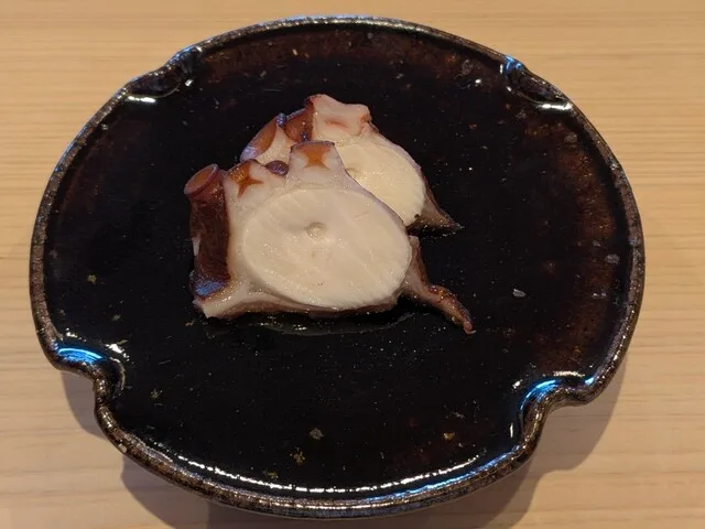 스시 호시야마의 검은 접시에 담긴 문어 슬라이스