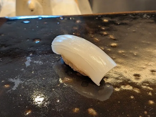 스시 호시야마의 검은 접시에 놓인 오징어 초밥