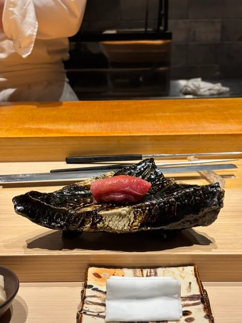 카타오카 아츠시의 검은 접시 위의 분홍빛 참치 초밥