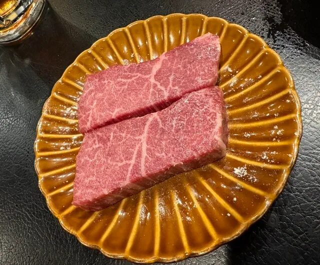 쿄쇼우란 혼점의 금빛 접시에 담긴 마블링 있는 소고기 두 조각
