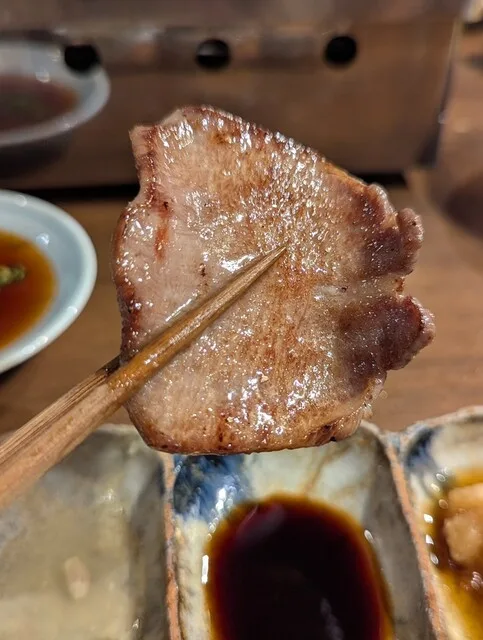 쿄라쿠 야키니쿠 포메의 젓가락으로 집은 노릇하게 구운 우설