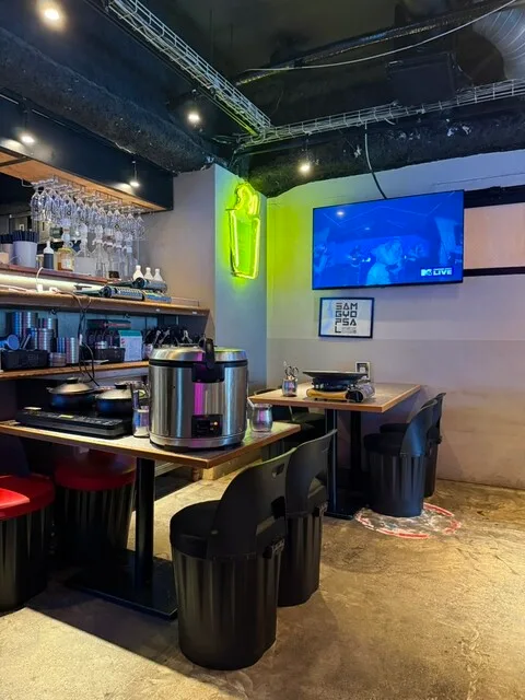 삼겹살 한식 바부 우메다점의 주방과 테이블, 벽걸이 화면이 보이는 실내