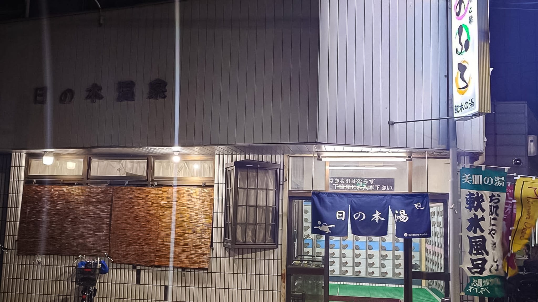 하얀 타일로 된 오래된 목욕탕 건물 정문이 열려 있다